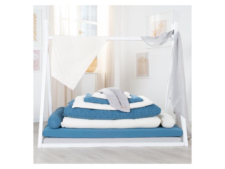 Weißes Tagesbett mit Himmel, blauer und weißer Bettwäsche und Nackenrollen.