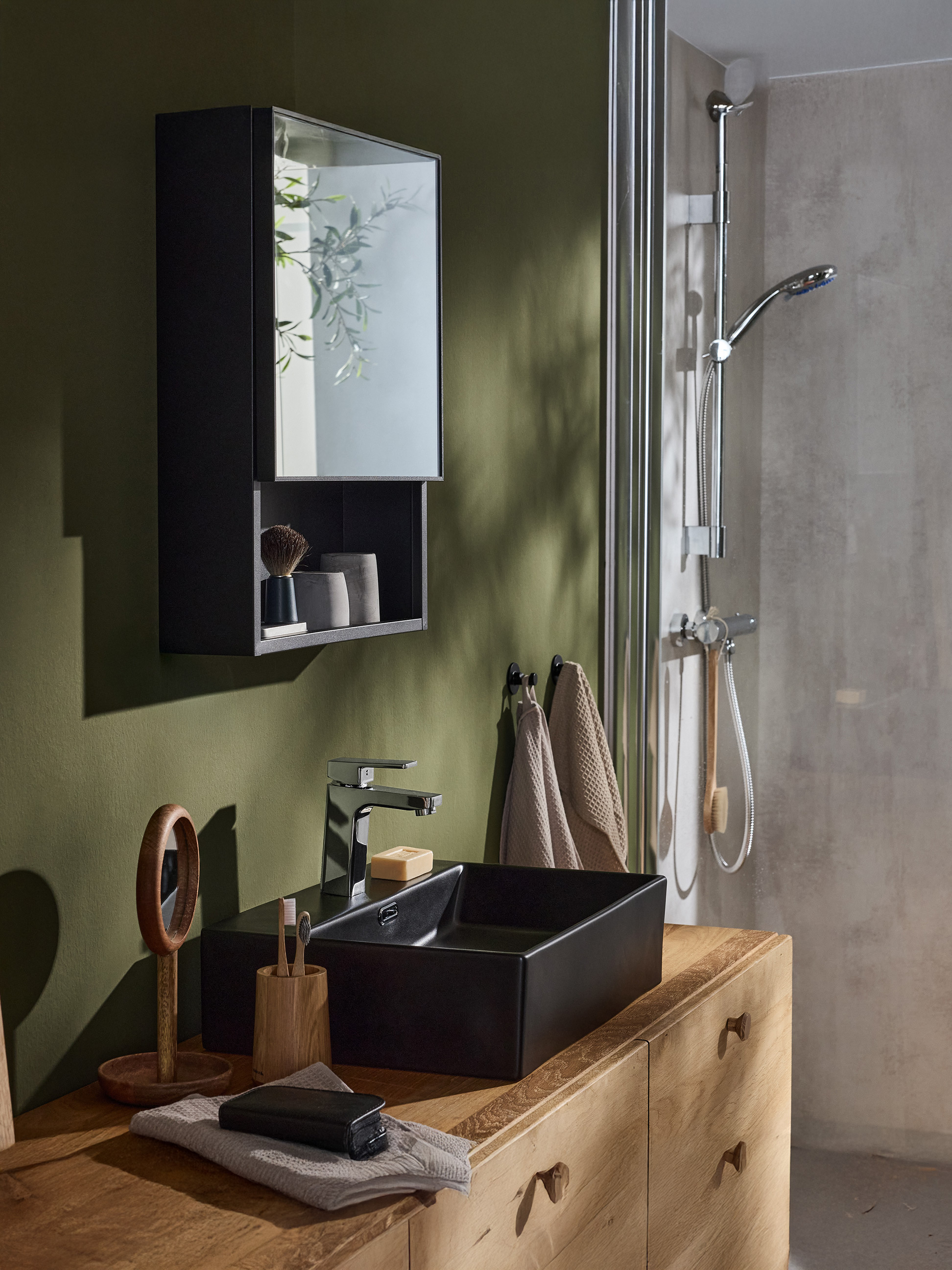 Ein modernes Badezimmer mit einem schwarzen Schrank, einem schwarzen Waschbecken, einem Chromhahn und einer Dusche.