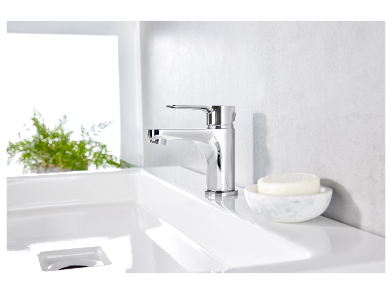 Moderne Badezimmerarmatur und Marmor-Seifenschale auf einem weißen Waschbecken.