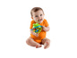 Ein Baby in einem orangenen Strampler spielt mit einer grünen Frosch-Rassel.