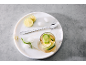 Erfrischendes Getränk mit Limetten- und Gurkenscheiben, Eiswürfeln und einem langen Löffel auf einem weißen Tablett.