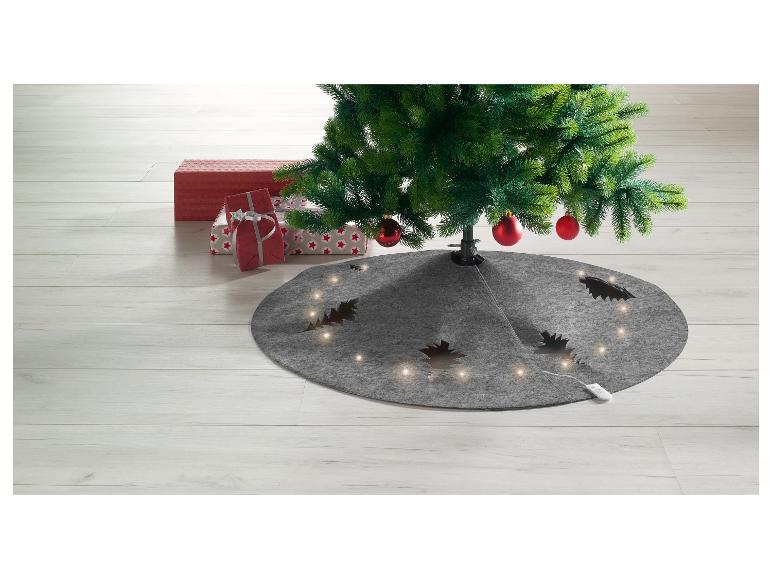 Weihnachtsbaum mit rotem Schmuck, Geschenken und grauem beleuchteten Rock.