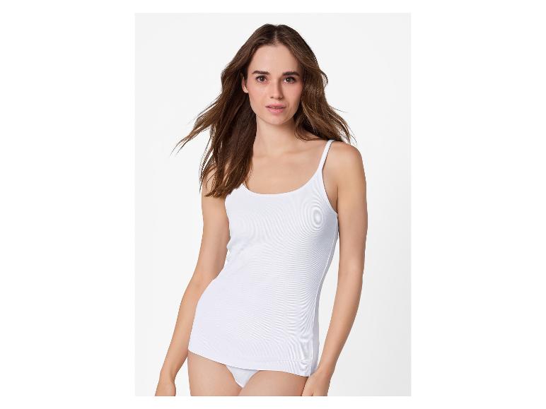 Frau in weißem Ripp-Tanktop und weißem Slip vor weißem Hintergrund.
