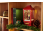 Weihnachtslaterne mit Weihnachtsmannfigur, Büchern und Tannengirlande auf einem Holzregal.