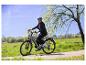 Frau mit Helm und Sonnenbrille auf einem E-Bike auf einem Feldweg.