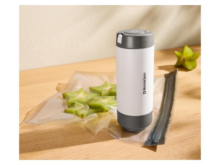 Vakuumbeutel mit Sternfrucht und ein tragbares Vakuumiergerät auf einem Holztisch.