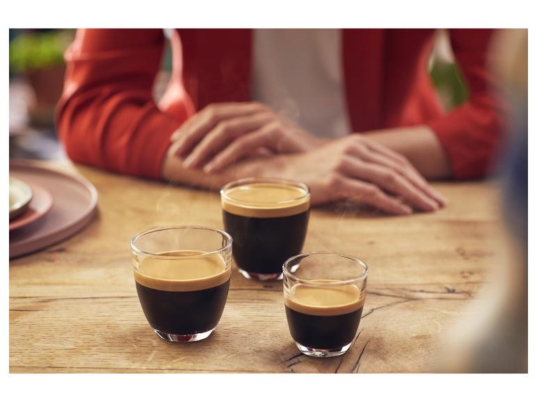 Drei dampfende Espressi auf einem Holztisch.