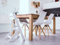 Ein Holztisch mit weißen Stühlen, darunter ein Hochstuhl