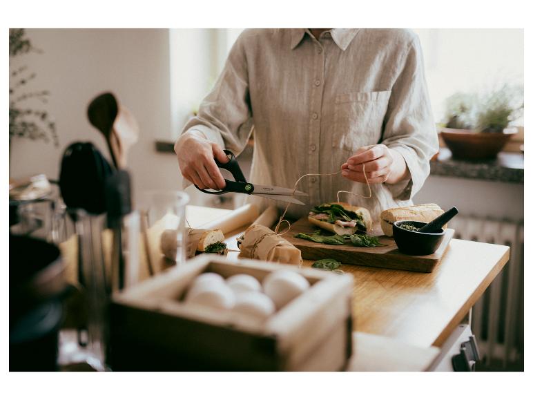 Person bereitet Baguette-Sandwiches mit Spinat und Fleisch zu und bindet sie mit Schnur.