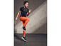 Eine Frau in einem schwarzen Top und orangefarbenen Leggings während einer Trainingseinheit.
