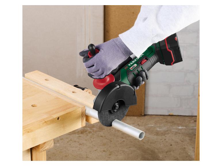 Parkside Akku-Winkelschleifer schneidet ein Metallrohr auf einer Holzwerkbank.