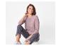 Lächelnde Frau in einem lila Langarmshirt und grauen Jeans, auf dem Boden sitzend.