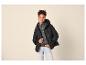 Frau in schwarzer Steppjacke, grauem Pullover und heller Jeans.