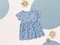 Ein Babykleid mit blauem Blumenmuster auf weißem Hintergrund.