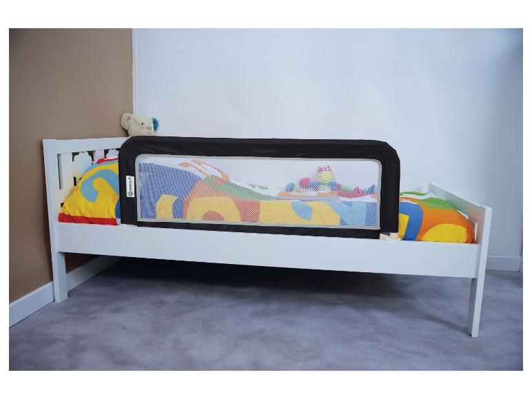 Weißes Kinderbett mit schwarzem Safety 1st Bettschutzgitter und bunter Bettwäsche.