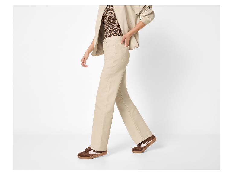 Frau in beiger weiter Hose, Leoparden-Top und braunen Sneakern.