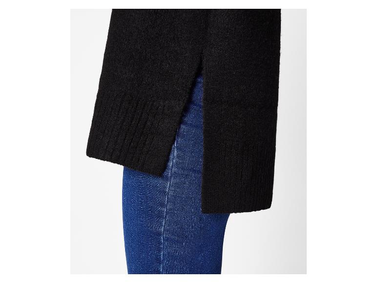 Schwarzer Pullover mit Seitenschlitzen über blauen Jeans getragen