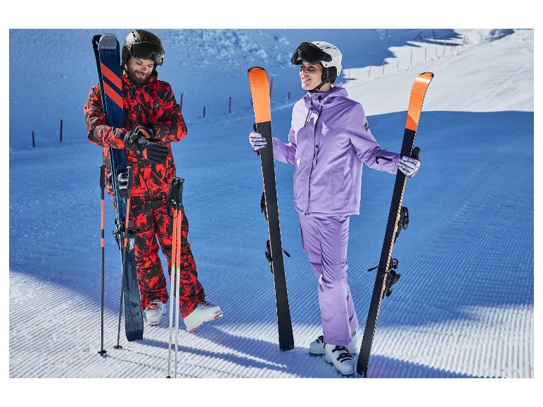 Zwei Skifahrer in farbenfrohen Skianzügen, mit Skiern und Stöcken, auf einer Skipiste.