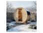 Outdoor-Holzfasssauna in einer verschneiten Landschaft mit Bäumen und Zaun.
