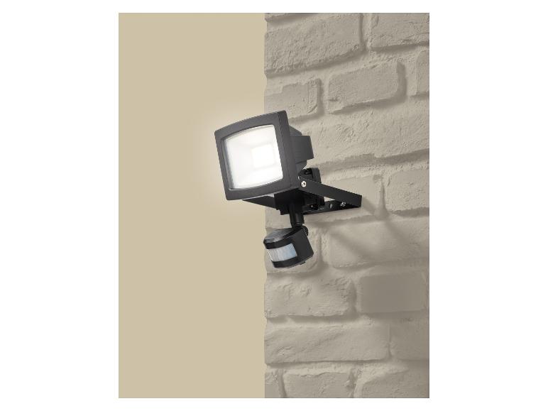 Außenstrahler mit Bewegungsmelder, an einer Ziegelwand montiert.
