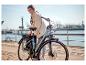 Frau mit Brille stellt ein graues E-Bike mit Korb an einem Dock ein.