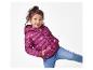 Lächelndes Mädchen in lila Herz-Steppjacke und blauen Jeans.