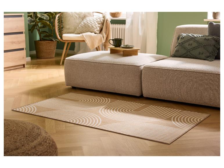 Wohnzimmer mit beigem Sofa, gemustertem Teppich und Holzmöbeln.