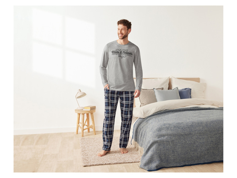 Mann in karierten Pyjama-Hosen und einem grauen Shirt mit dem Aufdruck 'Local Craft'.