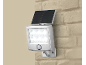 Silberne Solar-LED-Lampe mit Bewegungssensor, an einer beigen Ziegelwand montiert.