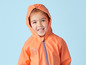 Ein Kind in einer orangefarbenen Regenjacke mit Kapuze.
