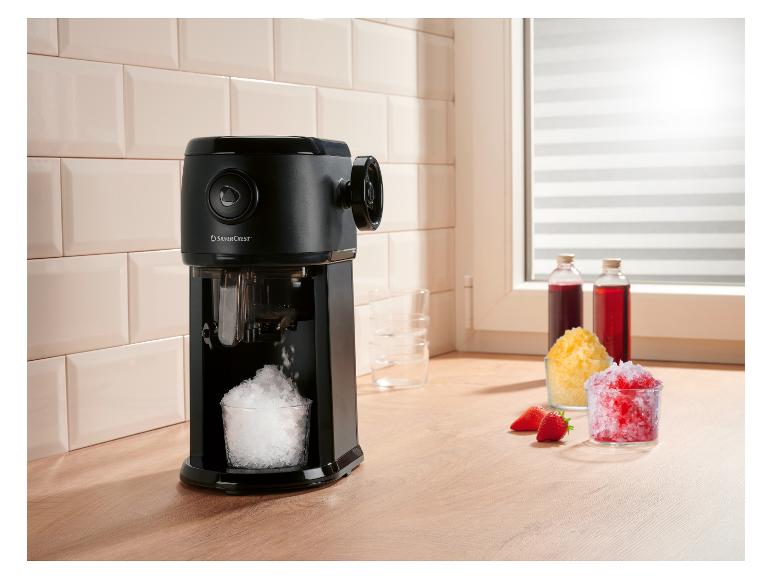 Schwarze Eismaschine mit Crushed Ice im Glas, Sirupen und Erdbeeren.