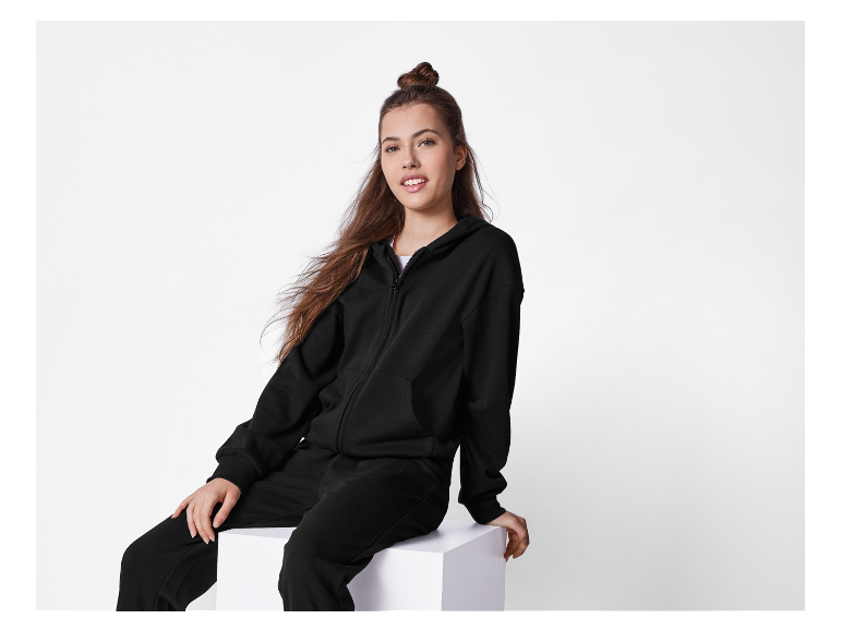 Ein Mädchen posiert in einem schwarzen Trainingsanzug.