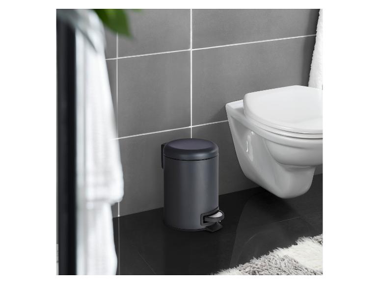 Dunkelgrauer Pedal-Mülleimer in einem Badezimmer neben einer wandhängenden Toilette.