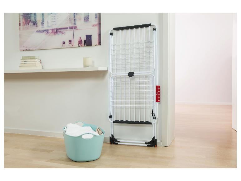 Weißer klappbarer Wäscheständer mit blauem Wäschekorb in einem hellen Raum.