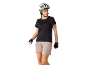 Frau in weißem Fahrradhelm, schwarzem T-Shirt und beigen Shorts, mit Radhandschuhen.