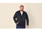 Lächelnder Mann in dunkelblauem Reißverschluss-Sweatshirt und Jeans.