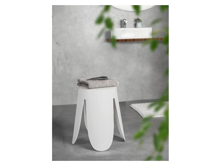 Moderner weißer Hocker mit Handtuch und Kosmetik im Badezimmer.