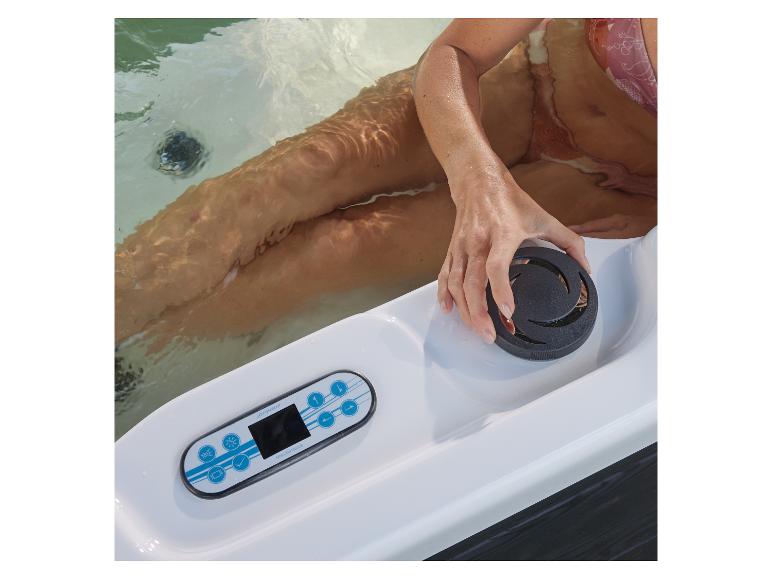 Frau im Whirlpool mit Bedienfeld und Wasserstrahlregler.