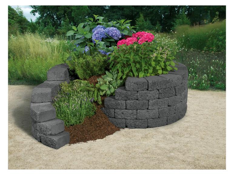 Rundes Steinbeet mit bunten Blumen und grünen Pflanzen.