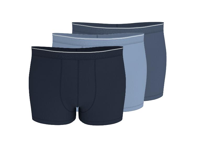 Drei Herren-Boxershorts in Blautönen, diagonal angeordnet.