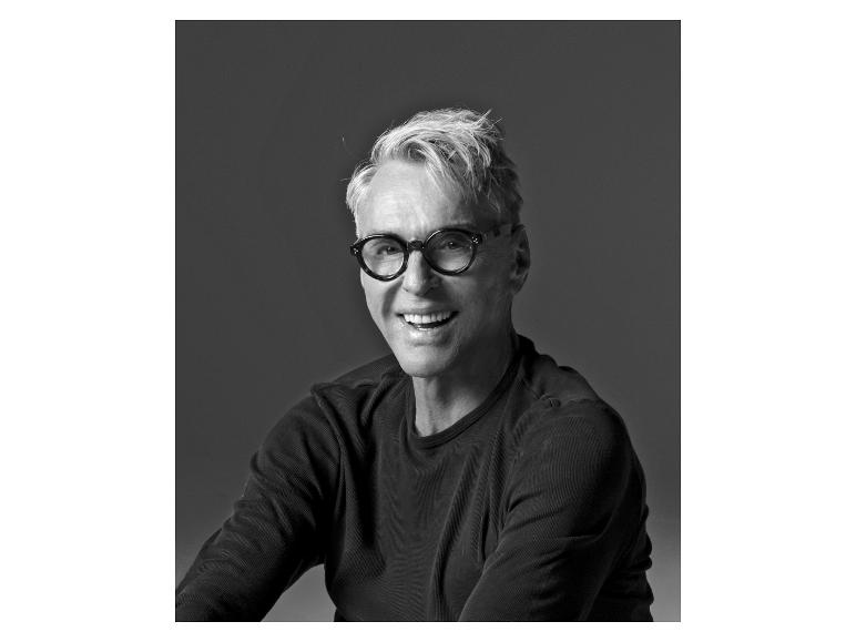 Lächelnder Mann mit Brille und dunklem Langarmshirt.