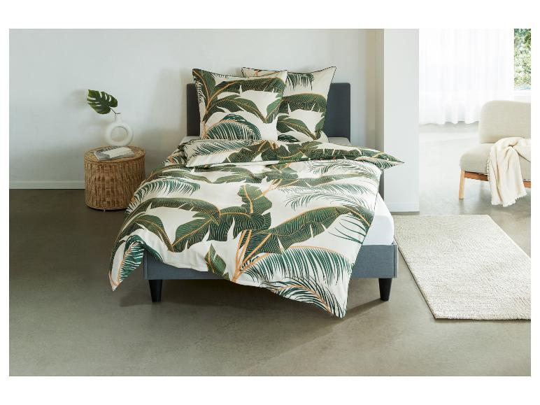 Ein Bett mit tropischer Bettwäsche mit Palmblättern
