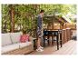 Mann kocht auf einer Outdoor-Grillplatte auf einer Terrasse mit Sofa und Pflanzen.