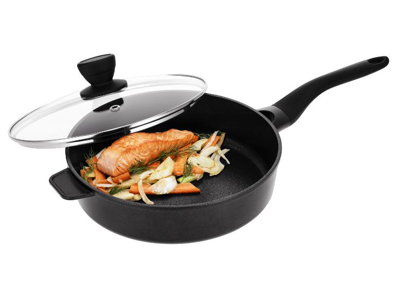 Schwarze Bratpfanne mit Glasdeckel, enthält Lachs und Gemüse.