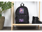 Schwarzer Rucksack mit K-Pop Demon Hunters-Aufdruck auf einem Holzregal neben Stiefeln.