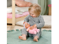 Ein Kleinkind spielt mit einer weichen Baby-Puppe auf einem grünen Teppich.