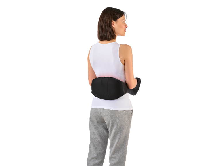 Frau mit elektrischem Lendenwirbel-Massagegerät und grauer Jogginghose.
