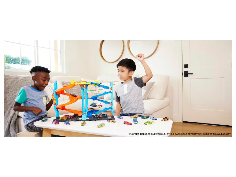 Zwei Kinder spielen mit einem Hot Wheels Garagen-Spielset und mehreren Spielzeugautos.