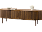 Holzfarbenes ovales Sideboard mit Lamellentüren, einer Dekoschale, Buch und Vase darauf.