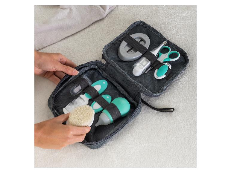 Hände ordnen ein Babypflegeset mit Bürste, Kamm, Thermometer, Schere und Nagelschere.